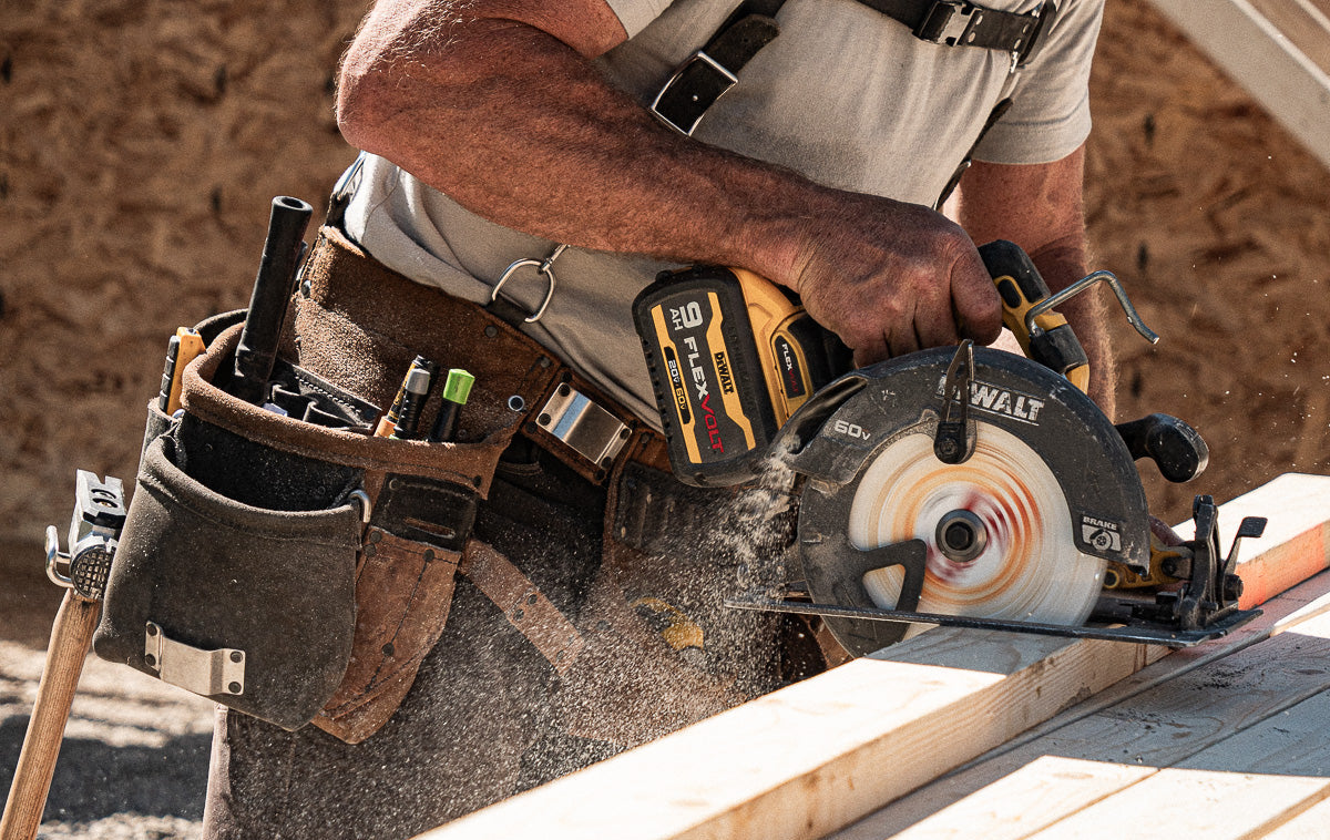 Person using a Dewalt circular saw on a wooden surface with a tool belt.
