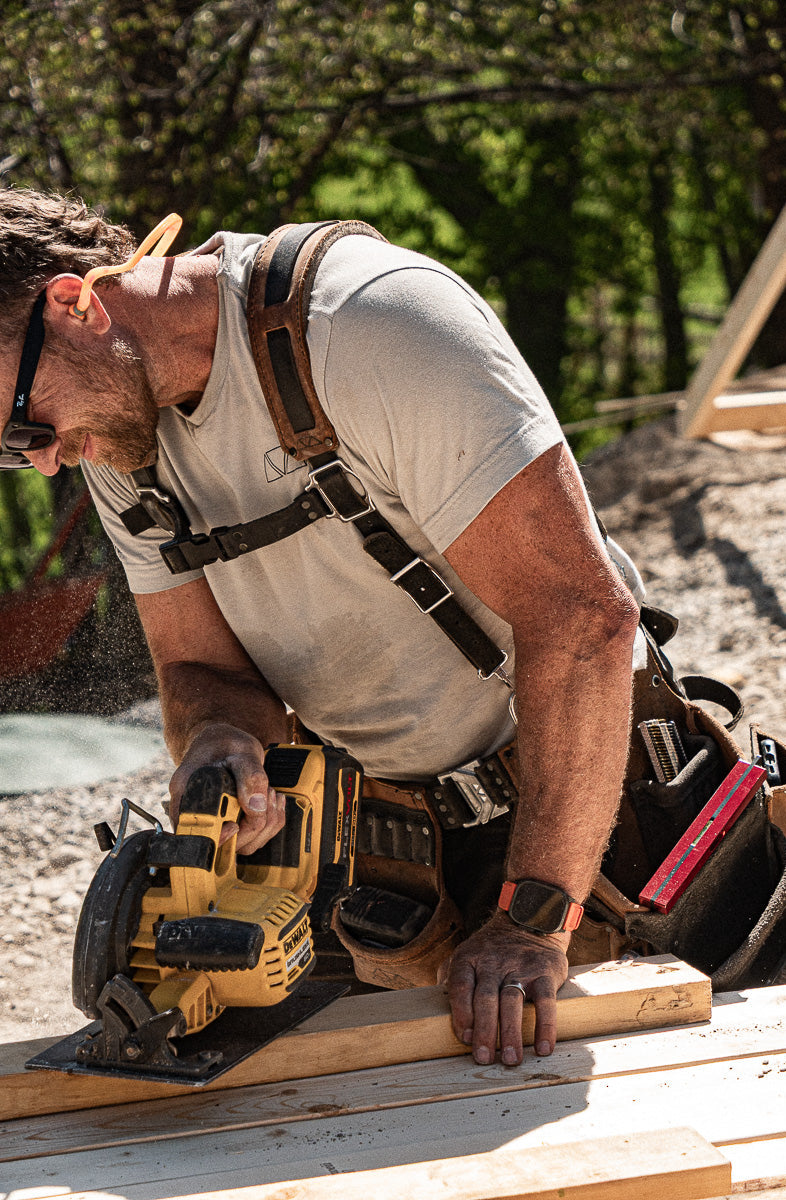 Man using a power saw on wooden planks outdoors